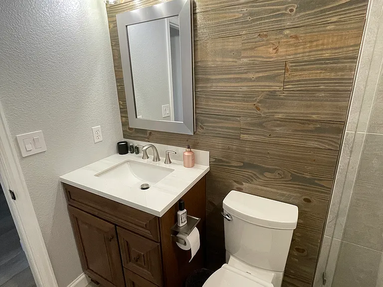 Vanity with stone top, mirror with medicine cabinet, and a soft close elongated toilet