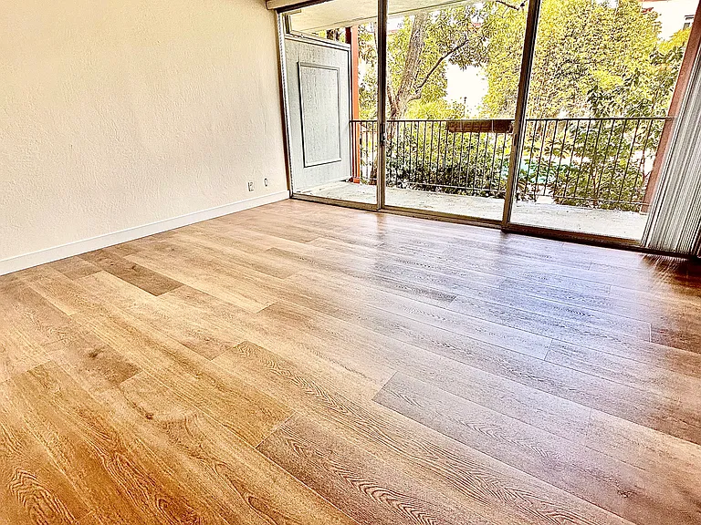 Unit #115 huge similar living room with brand-new luxury vinyl flooring and large private balcony overlooking the pool and landscaped gardens!