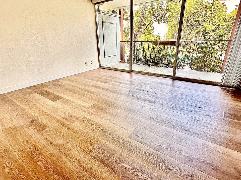 Unit #115 huge similar living room with brand-new luxury vinyl flooring and large private balcony overlooking the pool and landscaped gardens!