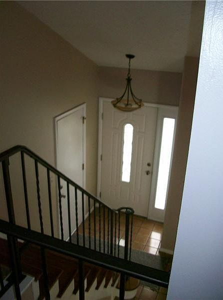 Inviting entry hall from the upstairs walkway with rod iron railings and updated light fixture
