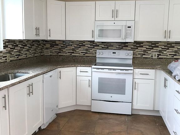 Large new kitchen cabinets and granite countertops with space for dining table.