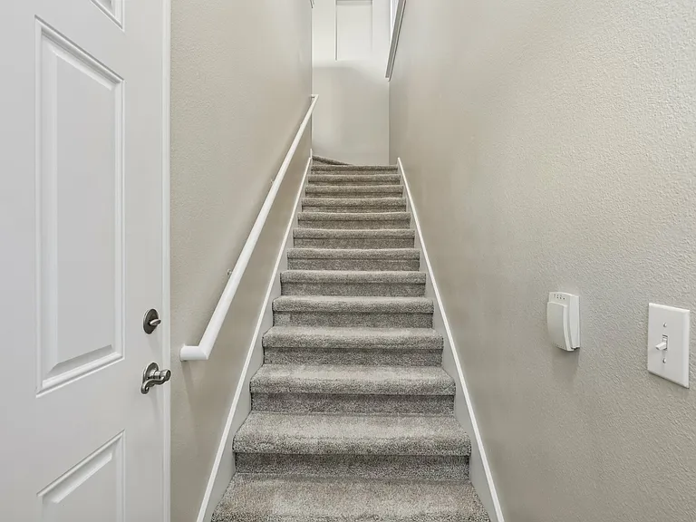 Welcoming staircase with plush carpet and modern handrail, leading to the upper level of a stylish apartment. Welcoming staircase with plush carpet and modern handrail, leading to the upper level of a stylish apartment.