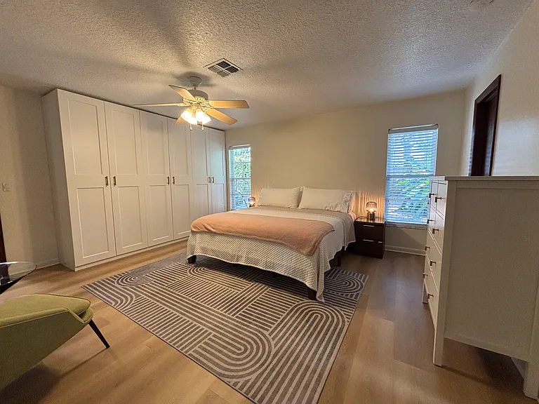 Wall of closets, dresser and king bed.