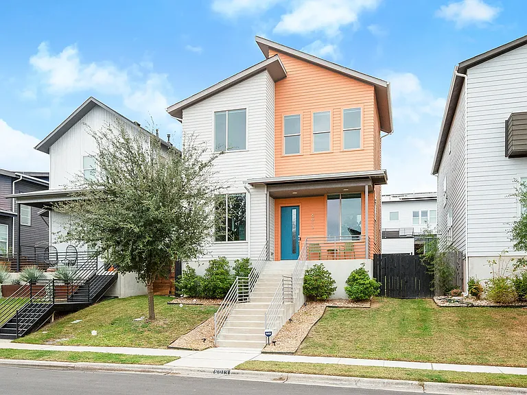 Charming curb appeal with a welcoming front porch, vibrant teal and orange accents, and a warm, modern exterior that stands out in the neighborhood.
