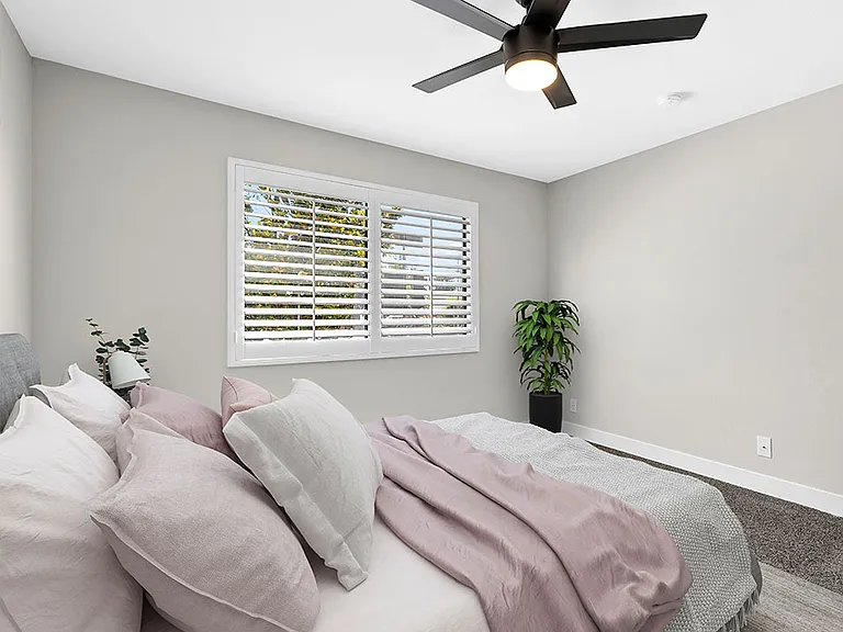 Carpeted bedroom with ceiling fan and large windows.