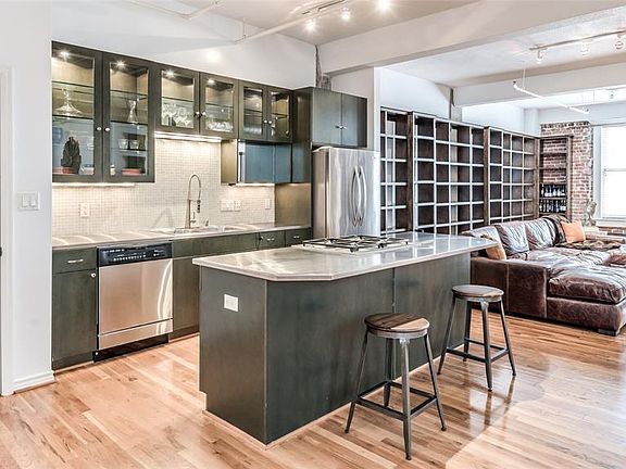 Kitchen with island and commercial style stainless steel countertops adds to industrial loft feel. For times you do not want to cook, you are steps away to numerous restaurants and food halls. Living Room windows look over Main Street.