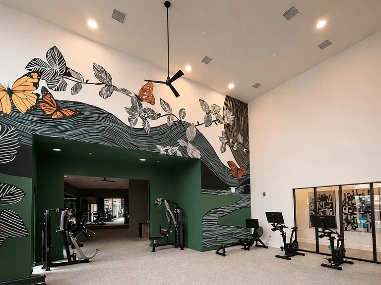 A bright, spacious fitness center designed for both cardio and strength training, featuring high ceilings, natural light, and modern equipment.
