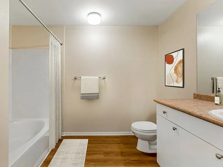 Renovated Package I bath with neutral laminate countertop, white cabinetry, and upgraded hard surface flooring