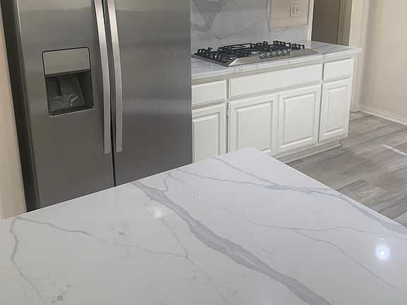 Gorgeous quartz counters and new cooktop with stainless steel refrigerator.