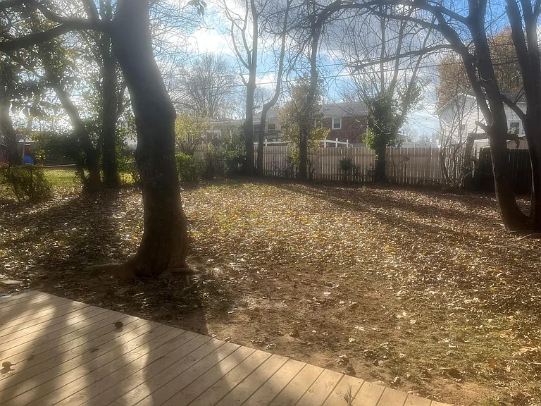 large fenced backyard with mature trees