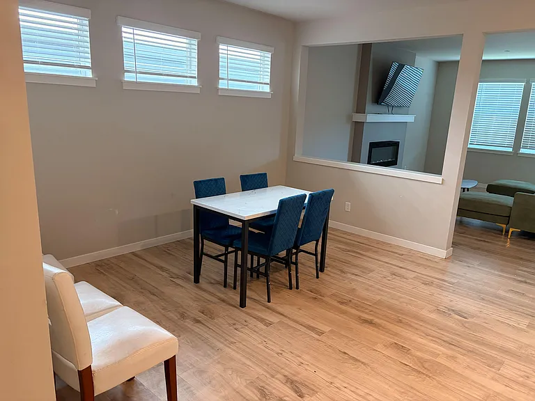 Open dining area with a four-seat table, hardwood-style floors, and interior pass-through overlooking the living space.