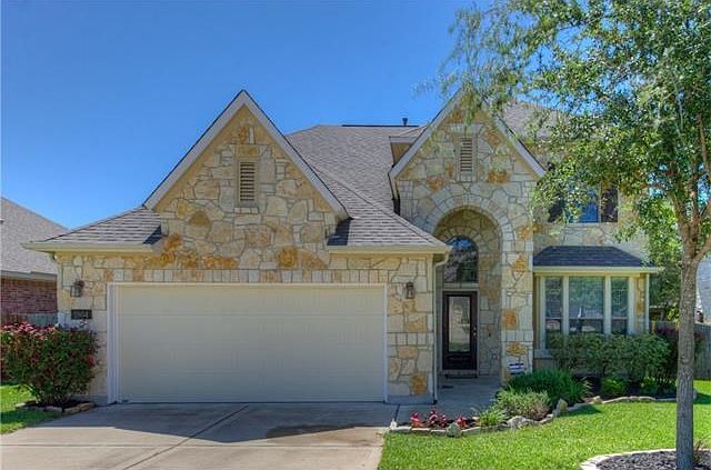Arriving home, you will feel like the king and queen returning to their glorious castle!  A beautiful stone veneer facade with high peaked roof lines and arched front entry are complimented by the lush green lawn, natural stone edged flower beds filled wi