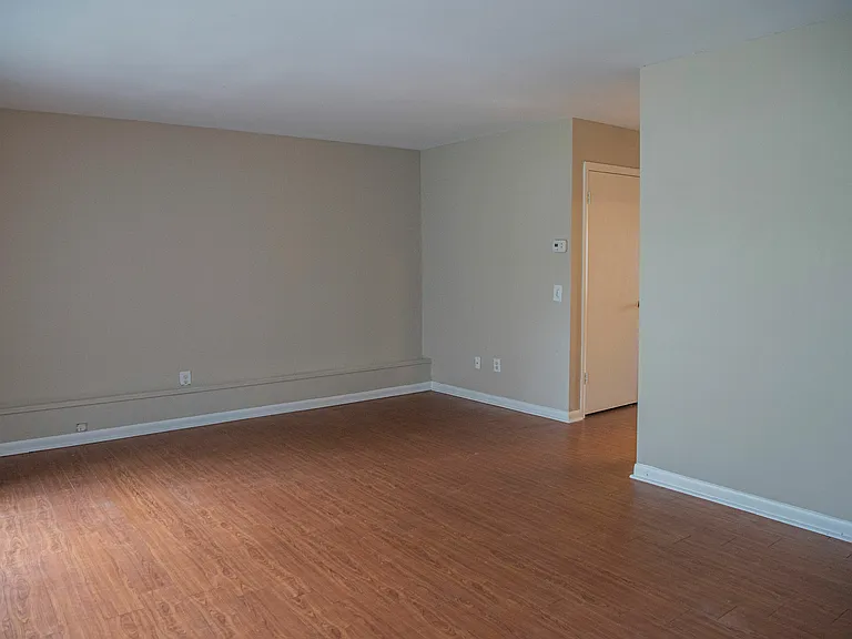 Spacious open living area with elegant hardwood flooring and neutral wall tones, perfect for custom decor.