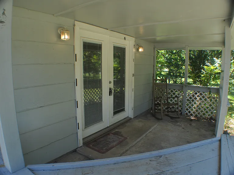 Covered back porch overlooks shady back yard.