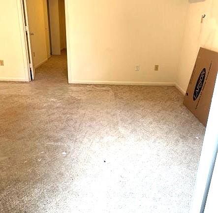 Living room immediately by the front door. 12.5'x13.5'. New minisplit AC and heater. New screen door is leaning on wall. Space is still to be painted.