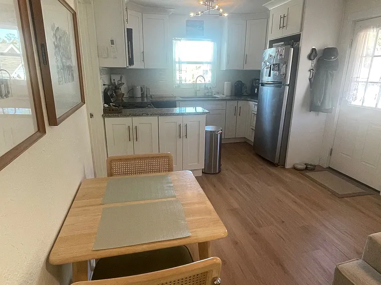 Looking at Kitchen area and front door from LR. Shows the brass light fixture and extra cabinets that open from LR side. Stove on other side of them.