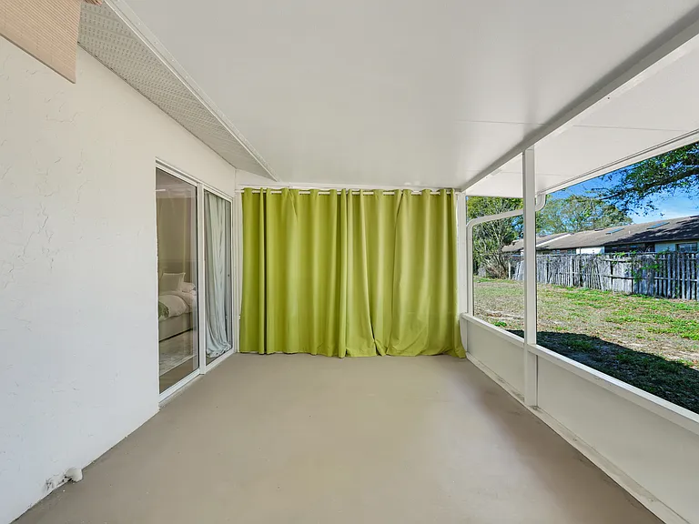 Spacious screened-in lanai, perfect for enjoying Florida's warm weather bug-free, with direct access from the primary bedroom and a side door to the backyard.