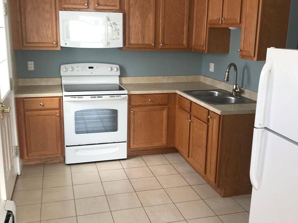 Modern kitchen with flat top stove, tile floor. Double sink with brushed nickel fixtures. Room enough for a very small table and chairs