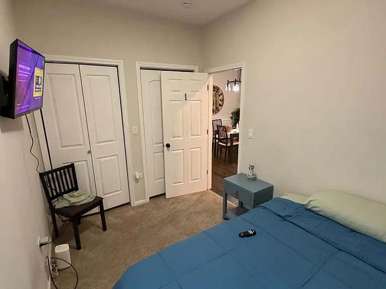 Private furnished bedroom with carpeted floors, wall-mounted TV, and a large closet, plus easy access to the main living area