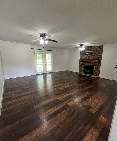 Living Room with gas logs surrounded by a rock fireplace and french doors leading to covered back porch