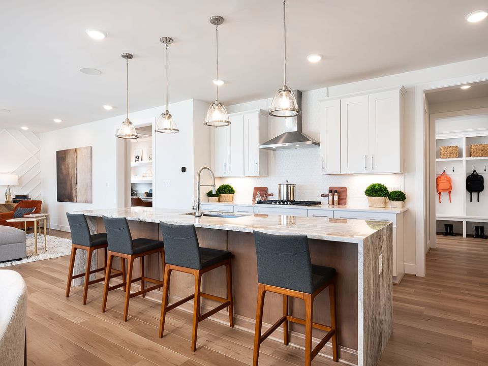 A modern, open-concept kitchen with white cabinets, wooden countertops, and pendant lights hanging a