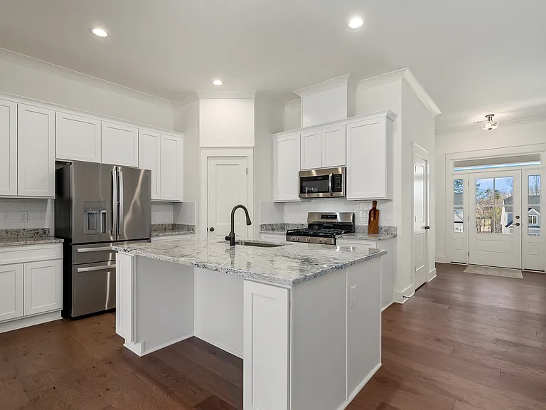 The kitchen is the heart of the home and delight in the extra large kitchen island with added storage, coffee/tea bar with prep sink, stainless steel appliances, plenty of white cabinets, granite tops, and a beautiful upgraded white backsplash.