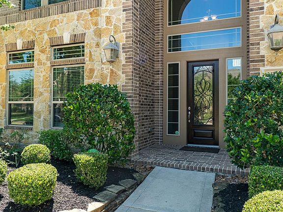 A beautiful brick and stone exterior lined with lush landscaping beckons you to this 2-story front porch with welcoming front door!
