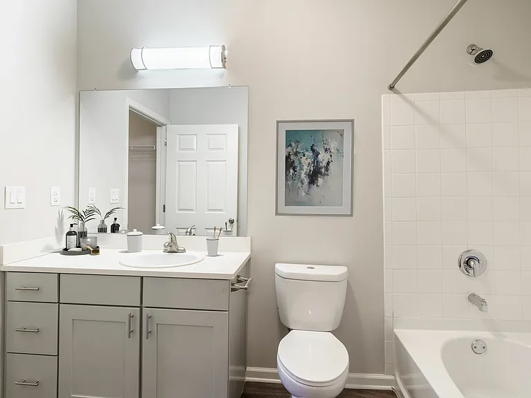 Modern bathroom with sleek white cabinetry, elegant wall art, and a bathtub for relaxation.