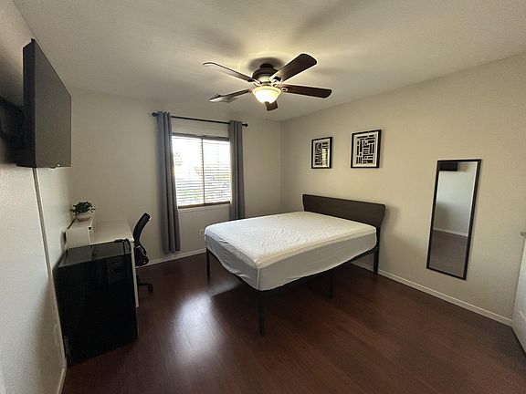 Spacious room with TV, Walk in closest, fridge, and desk area