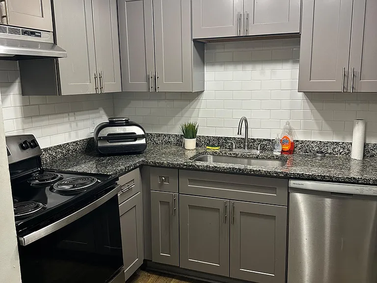 Updated kitchen with ample shaker cabinetry, granite-look counters, subway tile backsplash, and full appliance set.