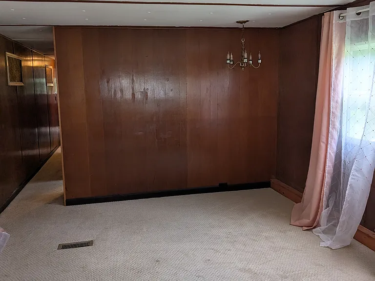 Looking from kitchen into dining room. Large double windows on both sides of dining room. Hallway on left.