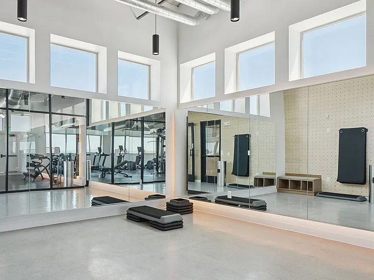 Find your flow in the dedicated yoga and movement studio featuring mirrored walls, natural light, and open workout space.