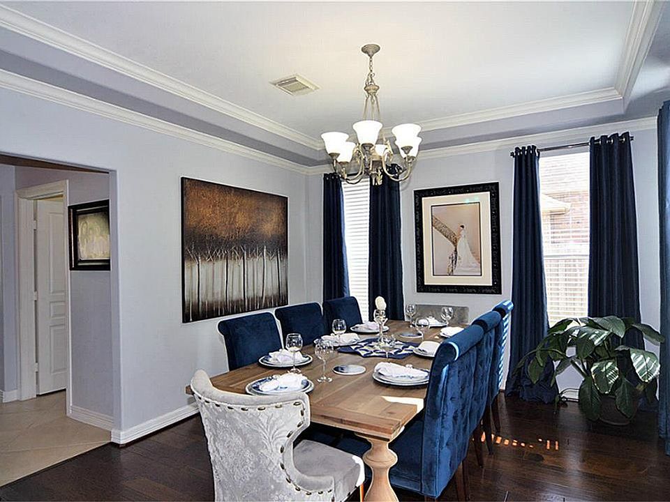 Well-lit and gracious dining room with crown molding and raised ceiling.