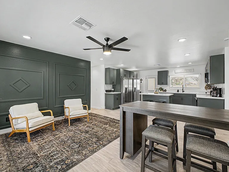 Open kitchen with island seating, ample cabinetry, and stainless appliances flows into a furnished common lounge area.