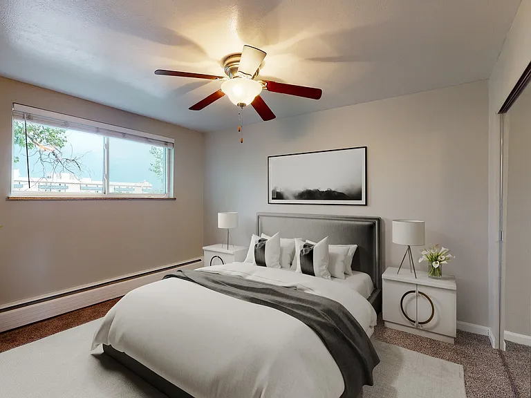 Inviting bedroom with elegant decor featuring a plush bed, modern ceiling fan, and ample natural light.