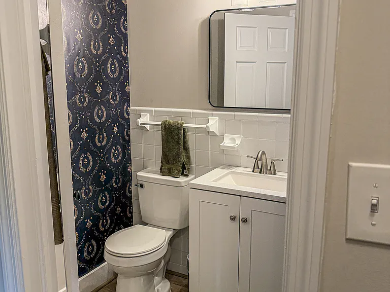 The guest bathroom just off the hallway of the two guest rooms features a full-tub/shower with new LVP floors, vanity, and equestrian-themed wallpaper.