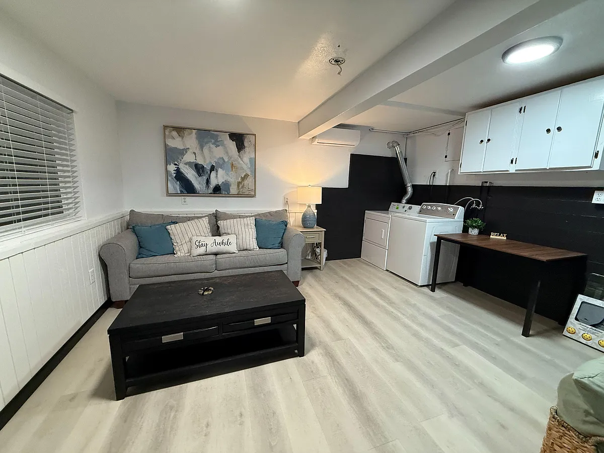 Finished lower-level lounge with seating area, table space, and in-room laundry plus cabinet storage. - State Highway 138