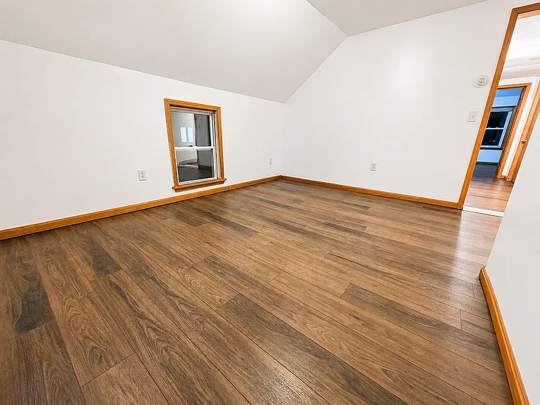 Spacious living area with warm wood-tone flooring and natural trim