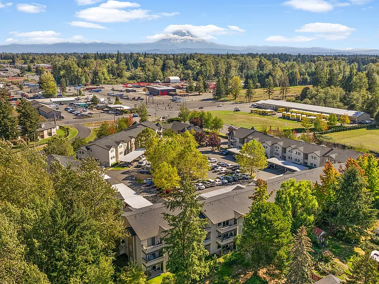 Aerial view of the apartment community surrounded by mature trees and scenic Northwest landscapes.