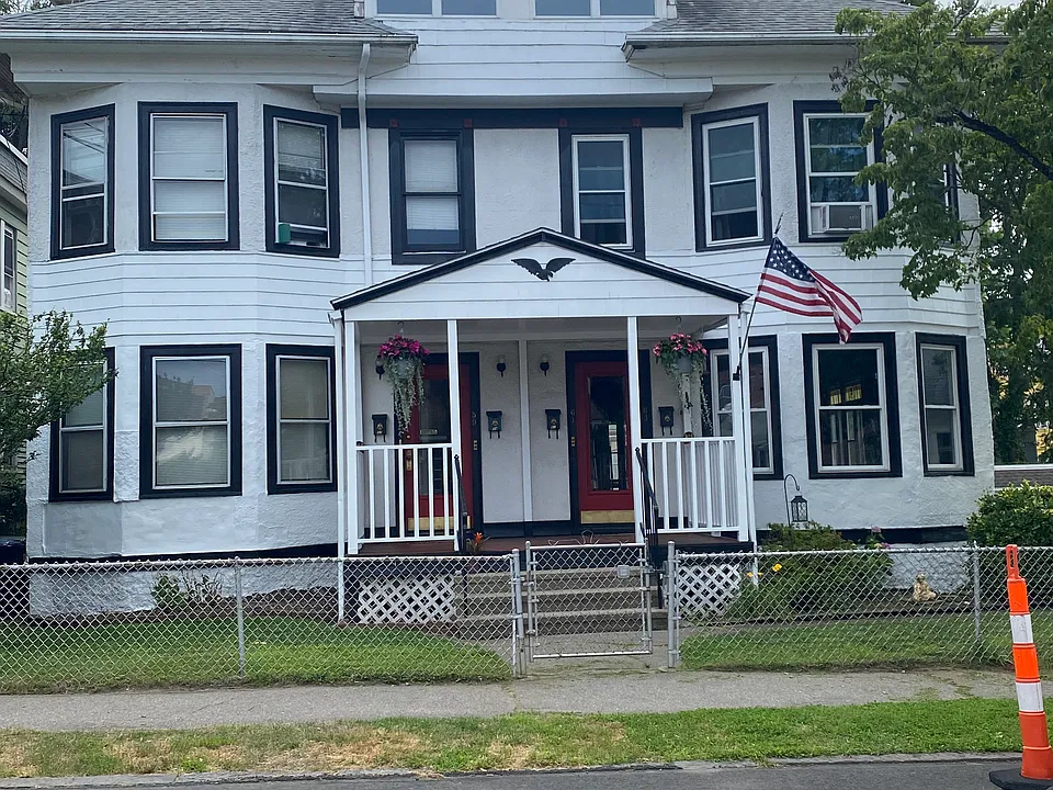 Front view of home shared fenced in yard, with fire pit in backyard