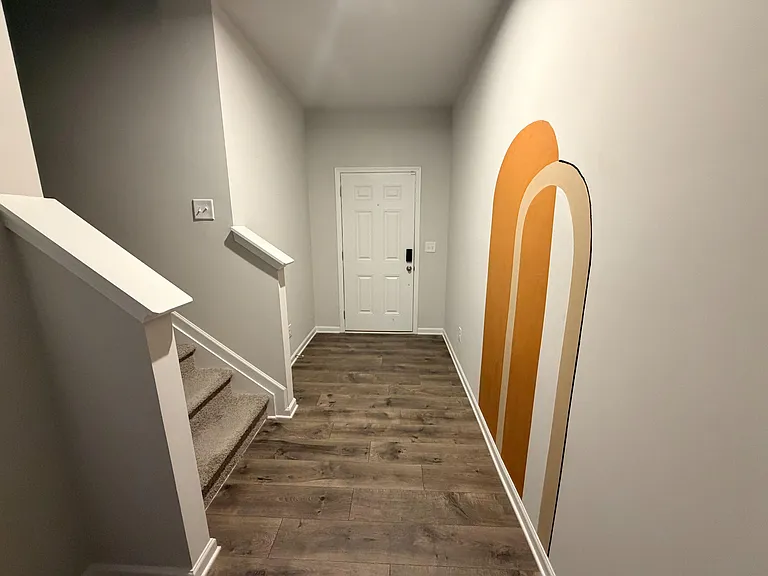 Entry foyer with durable plank flooring, stair access, and a welcoming front door area for easy coming and going.