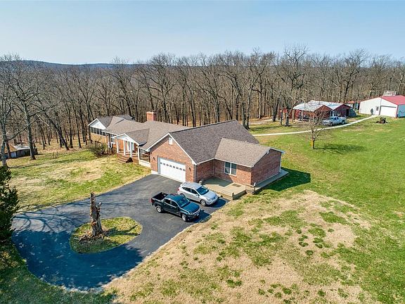 Aerial-Brick Ranch with walkway to both big barns and 2 car carport.