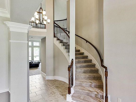 Grand entry features curving staircase with wrought iron balusters and trademark  rotunda with chandelier.