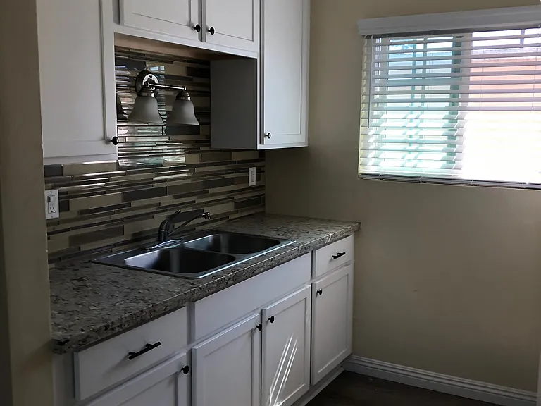 Newly installed kitchen Cabinets with stainless steel sink, splash wall and quartz countertop.
