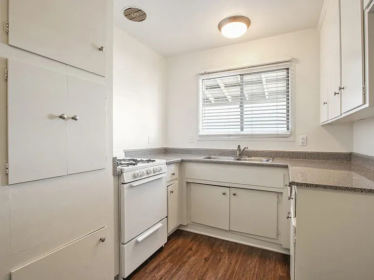 Kitchen with white gas stove, granite countertops, White kitchen cabinets