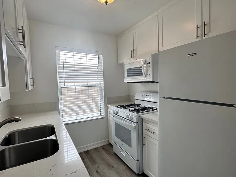 White Shaker cabinets, gas stove, refrigerator included, wood like flooring in the kitchen and dinning room.
