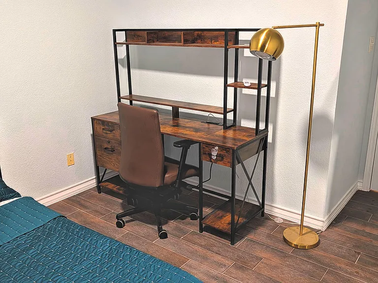 Bedroom includes a dedicated work area with desk, shelving, and task lighting, plus durable tile flooring and closet access.