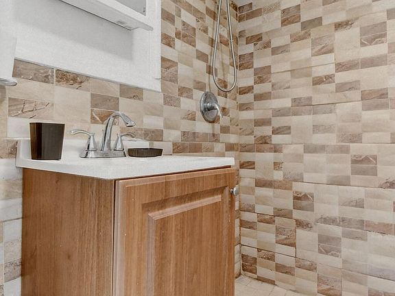 Bathroom features a tiled shower surround with handheld showerhead and a vanity with mirror for everyday convenience.