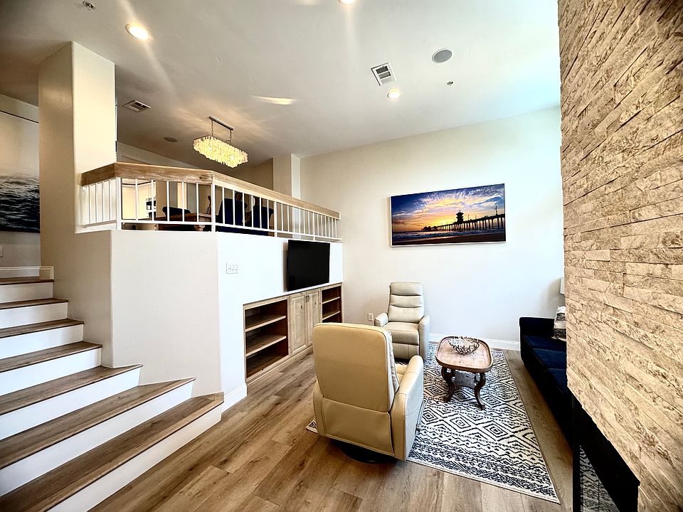 Built in tv credenza and beach wood floors with white stair under casing
