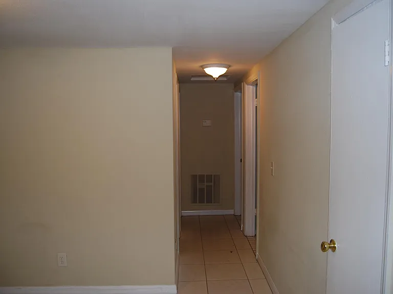 Hallway leading to two bedrooms on the right and one bedroom on the left.